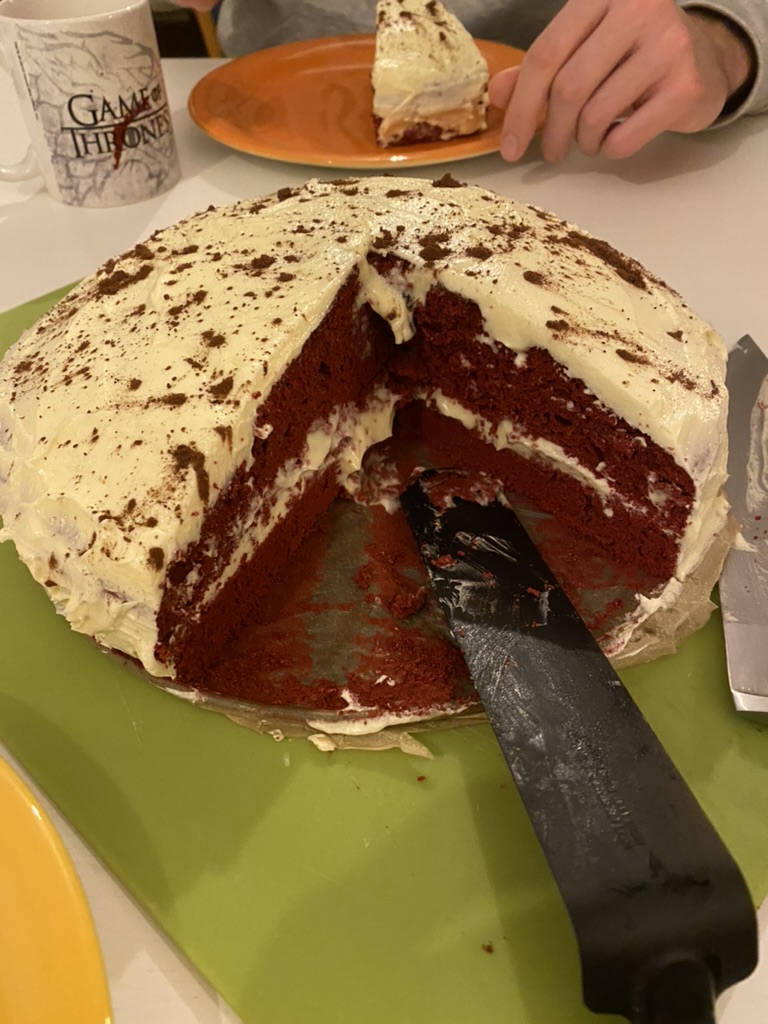 A red velvet cake with a large slice removed and a black cake server resting inside the opening.