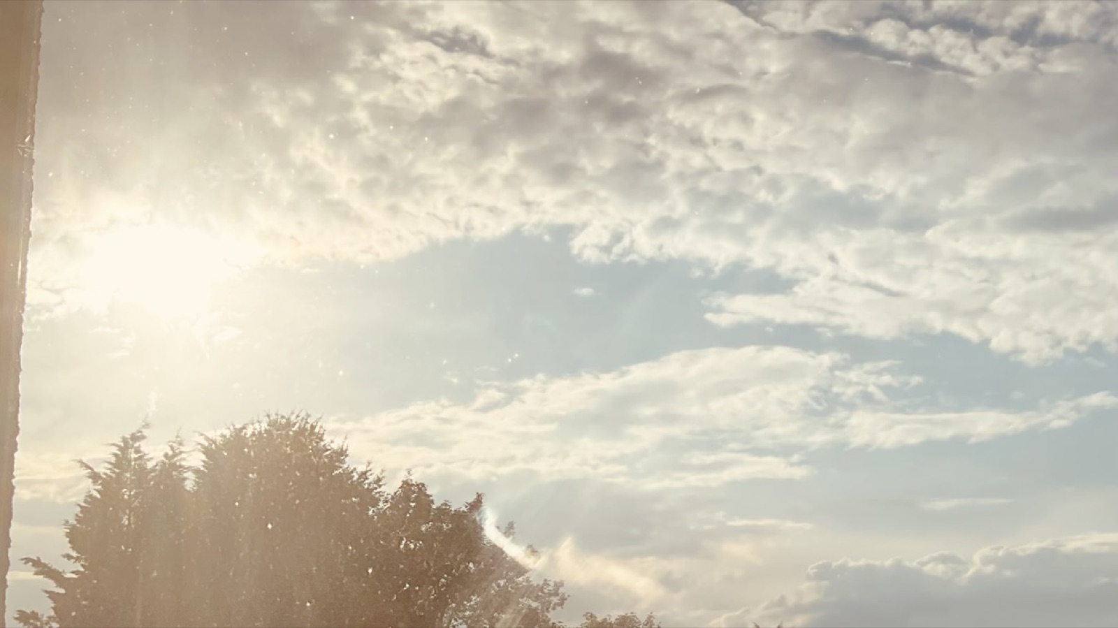 Sunlight breaks through layered blue-grey clouds above a dark horizon.